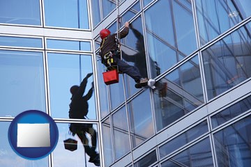 a window washer, washing office building windows - with Colorado icon