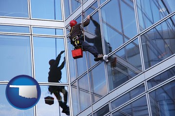 a window washer, washing office building windows - with Oklahoma icon