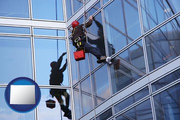 a window washer, washing office building windows - with Wyoming icon